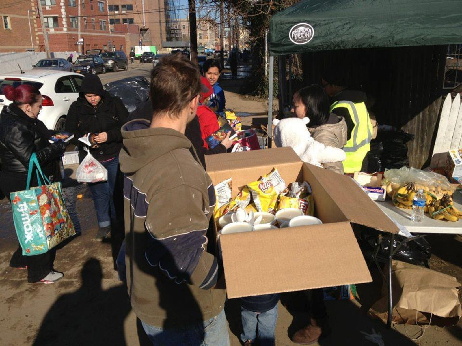 Food and supplies distributed under a canopy on a city sidewalk