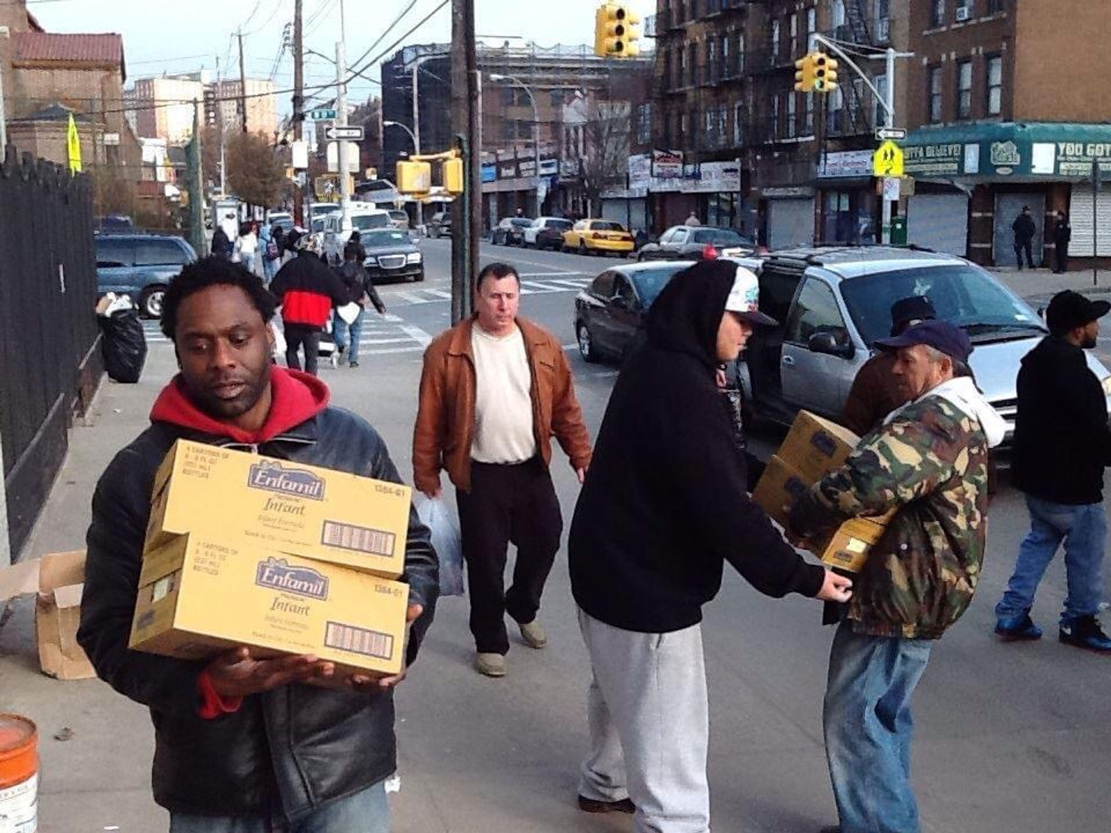 Volunteers carrying boxes of infant formula from a van