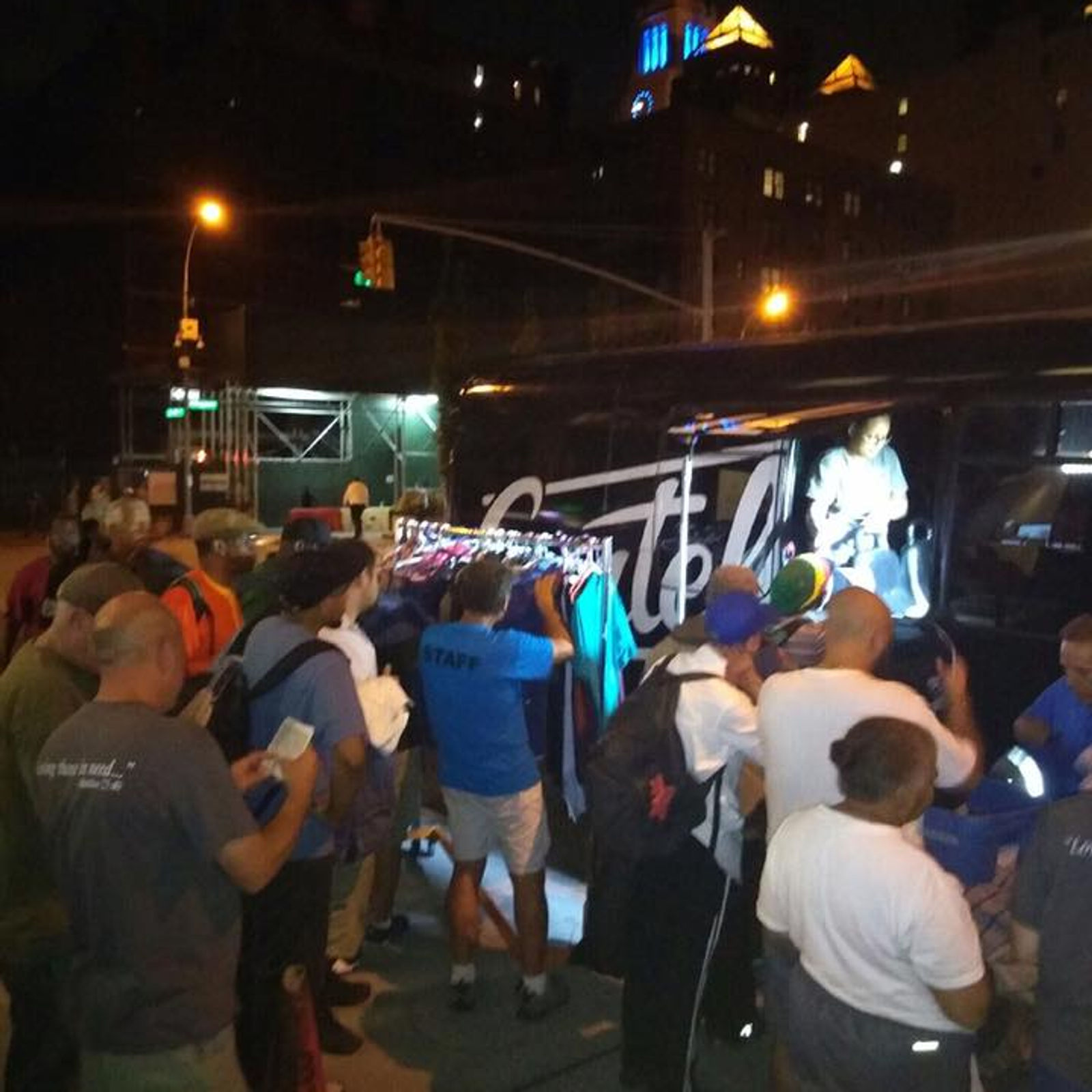 Staff at the clothing rack beside the outreach bus at night
